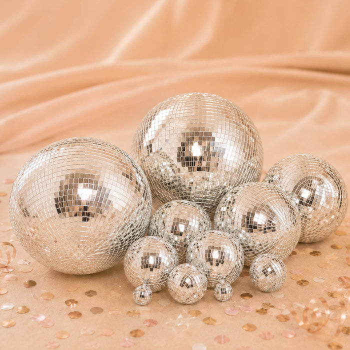 Silver disco balls on a peach background with scattered confetti