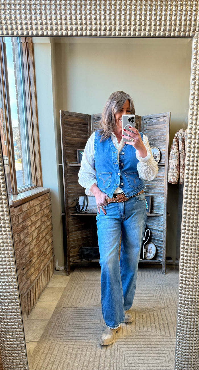 Light blue denim vest with stitched pockets and button front, paired with jeans
