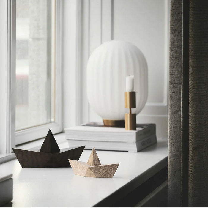 Two wooden boats on a surface with a modern lamp in the background.