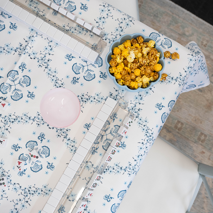 Aerial view of game table with blue and white patterned tablecloth, mahjong, and snacks.