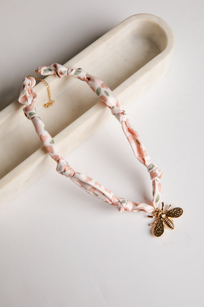 Necklace with bee charm on a light background