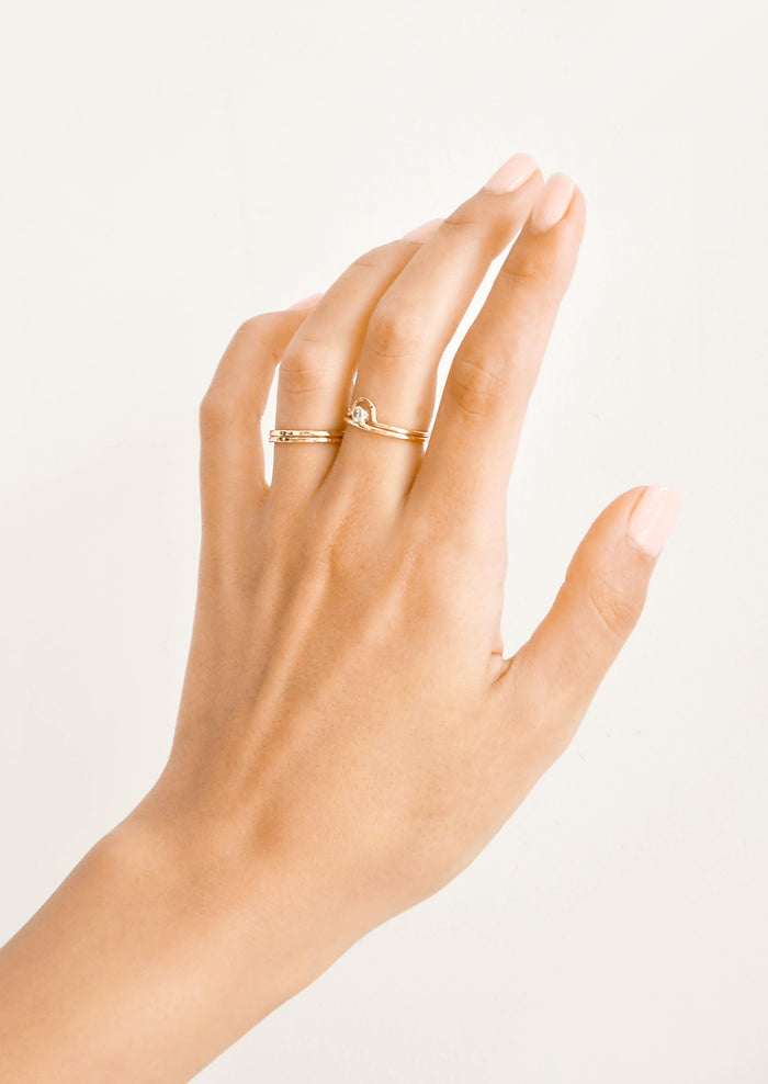 Woman's hand with gold rings on her ring and middle fingers.
