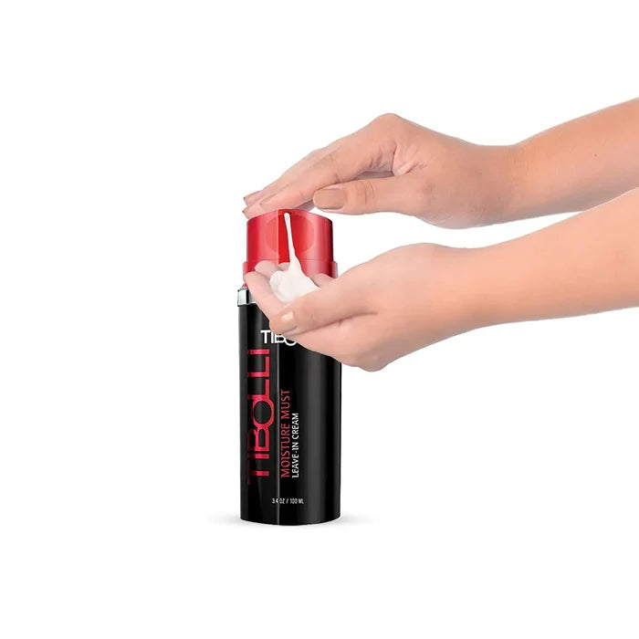 A person dispensing a creamy leave-in treatment from a sleek black bottle with a red cap labeled "TIBOLL Moisture Mist."