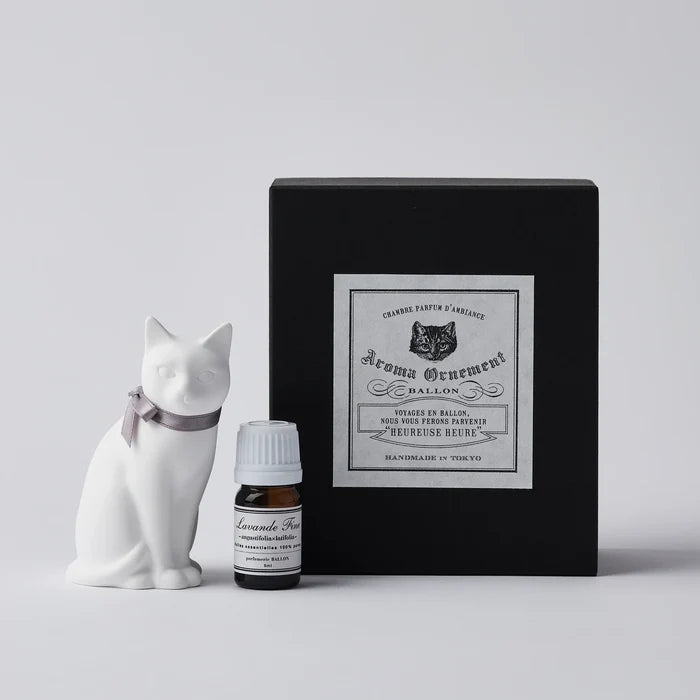 White cat-shaped aroma ornament gift set with a gray ribbon collar, essential oil bottle, and black vintage-style box, displayed on a clean white background in a minimalist home fragrance product presentation.