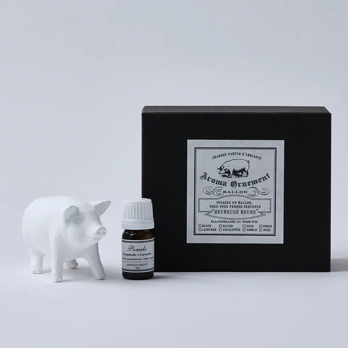 White pig-shaped aroma ornament gift set with essential oil bottle and black vintage-style box, displayed on a clean white background in a minimalist home fragrance product presentation.