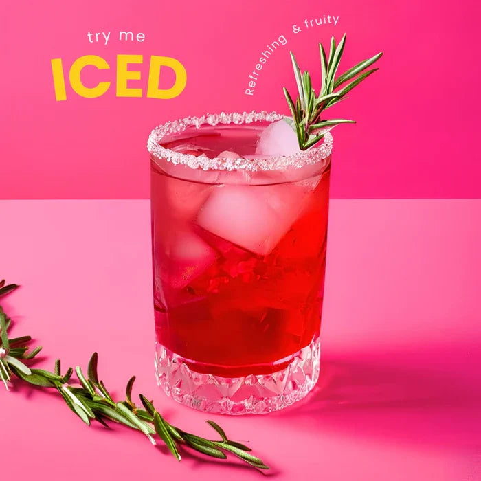 Red iced drink with a sprig of rosemary on a pink background, text 'try me ICED' and 'refreshing & fruity'.