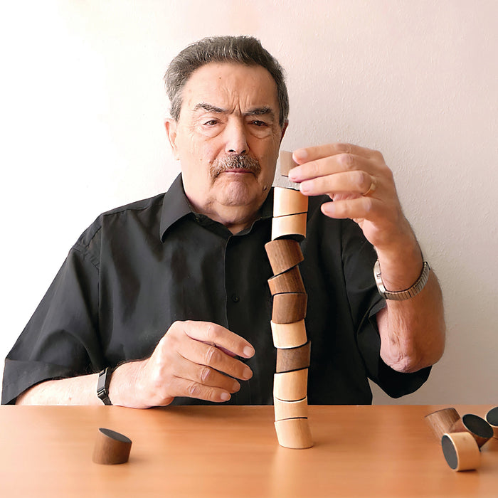 Man building a tower with wooden blocks on a table against a plain background