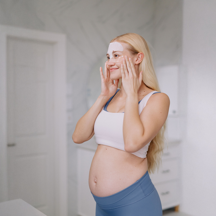 Pregnant woman applying Frownies Under Eye Gels in a bathroom