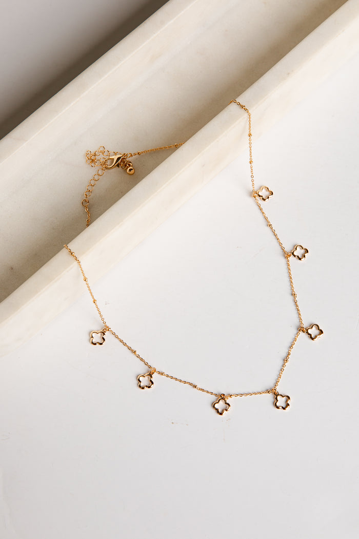 Gold necklace with star-shaped pendants on a white surface