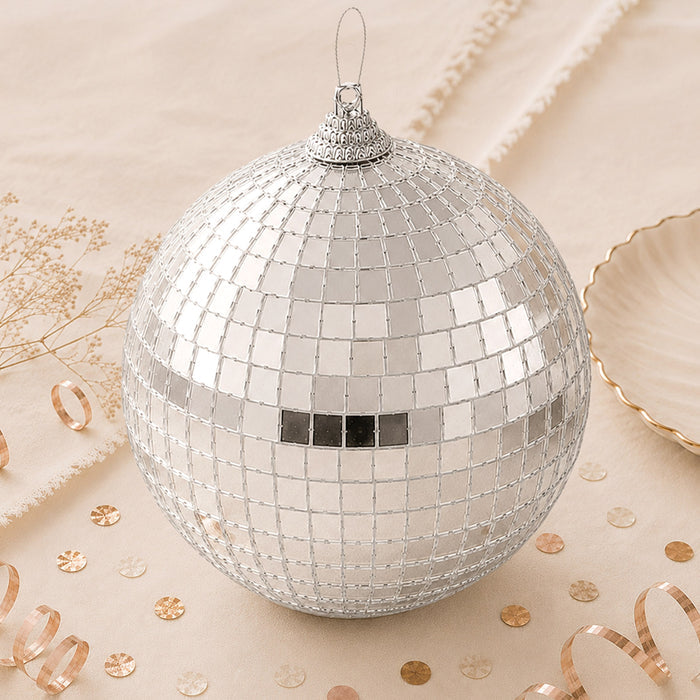 Silver disco ball ornament with mirrored tiles on a beige festive background