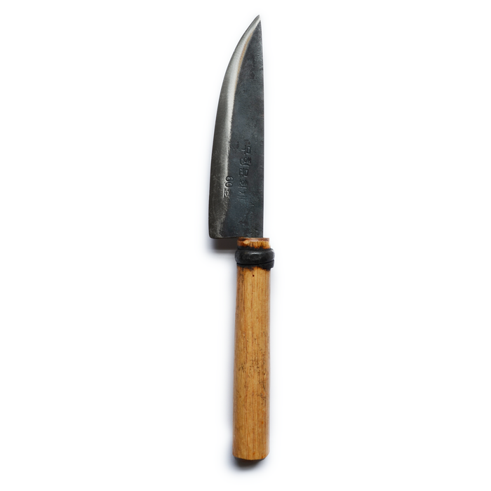Small hand-forged kitchen knife with a dark steel blade and light wooden handle, displayed on a clean white background in a minimalist artisan kitchen product presentation.