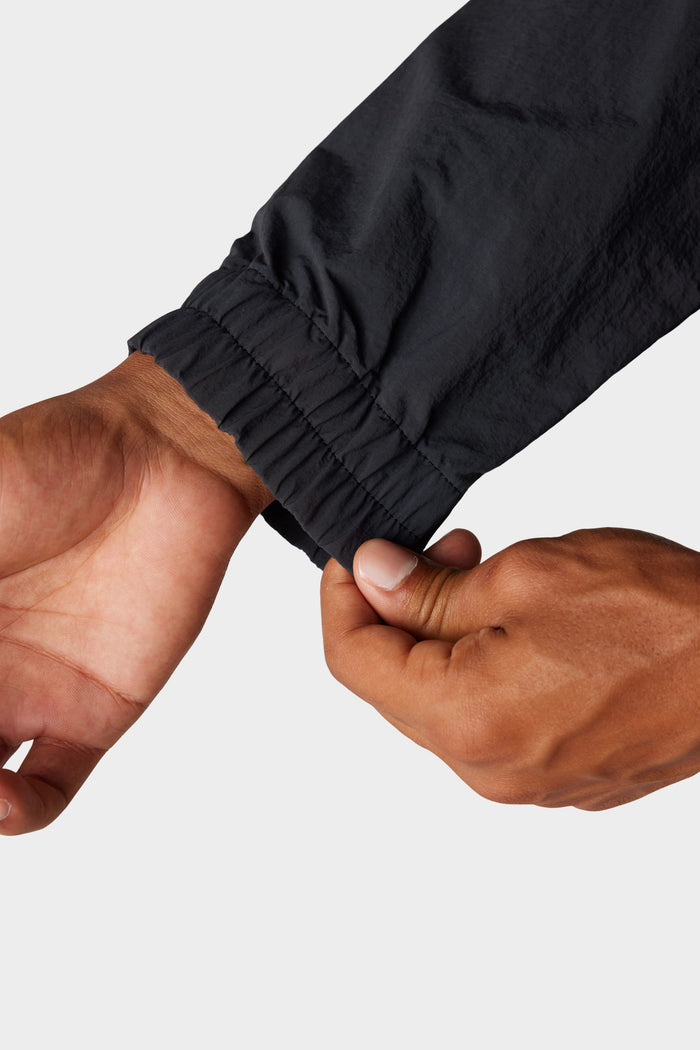 A close-up of two hands adjusting the cuff of the 686 Mens Buttermilk Sherpa Crew, highlighting its comfort and style against a plain light background.