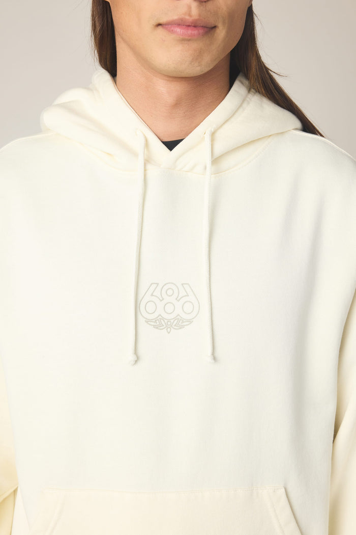 A person wearing the 686 Men's High Def Relaxed LS Hoody in a cream color, featuring a subtle 686 logo on the chest. The image is cropped at the nose and mid-torso, showing only the lower half of the face and upper body.