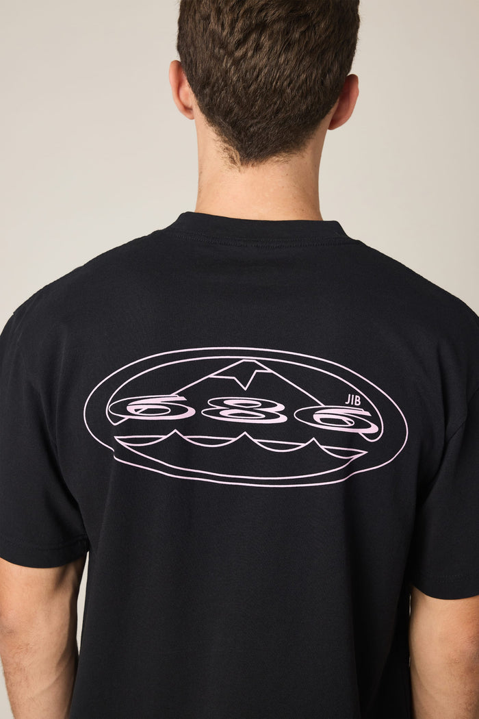 A person faces away, displaying the back of the 686 Men's Jib Relaxed SS Tee—a black 100% cotton t-shirt by 686, featuring a white graphic of waves, an upward arrow, and the letters "JIB" for a comfortable yet stylish look.