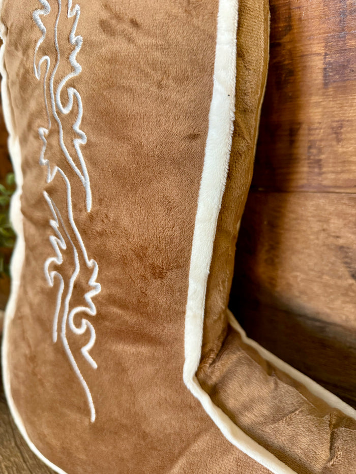 Tan boot-shaped pillow close-up: white piping and embroidered pattern on fabric