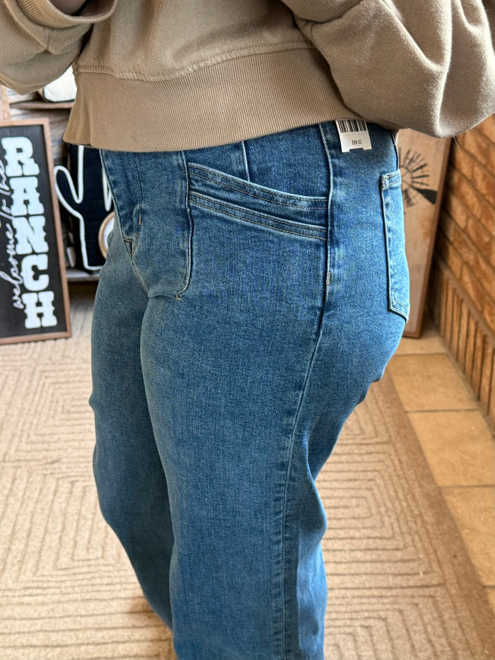 Blue wide-leg denim jeans with curved back yoke and slash pocket details