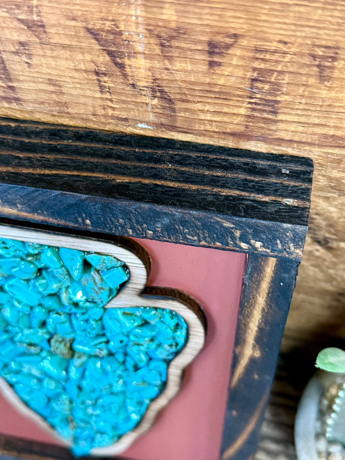 Turquoise arrowhead art detail in wood frame, teal stone chips over mauve backing