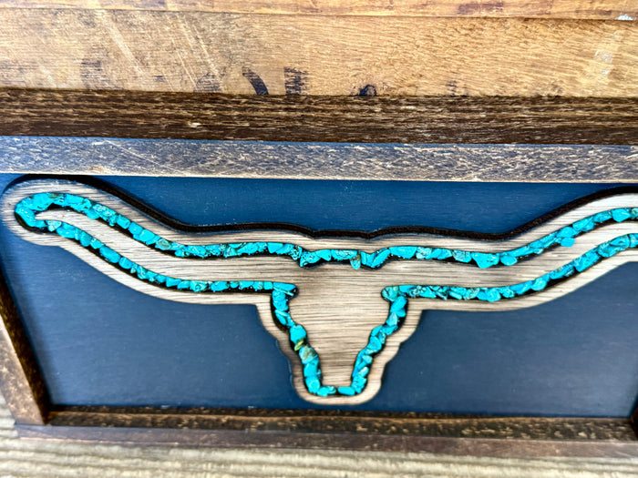 Turquoise longhorn wall art detail on blue panel inside dark wood frame