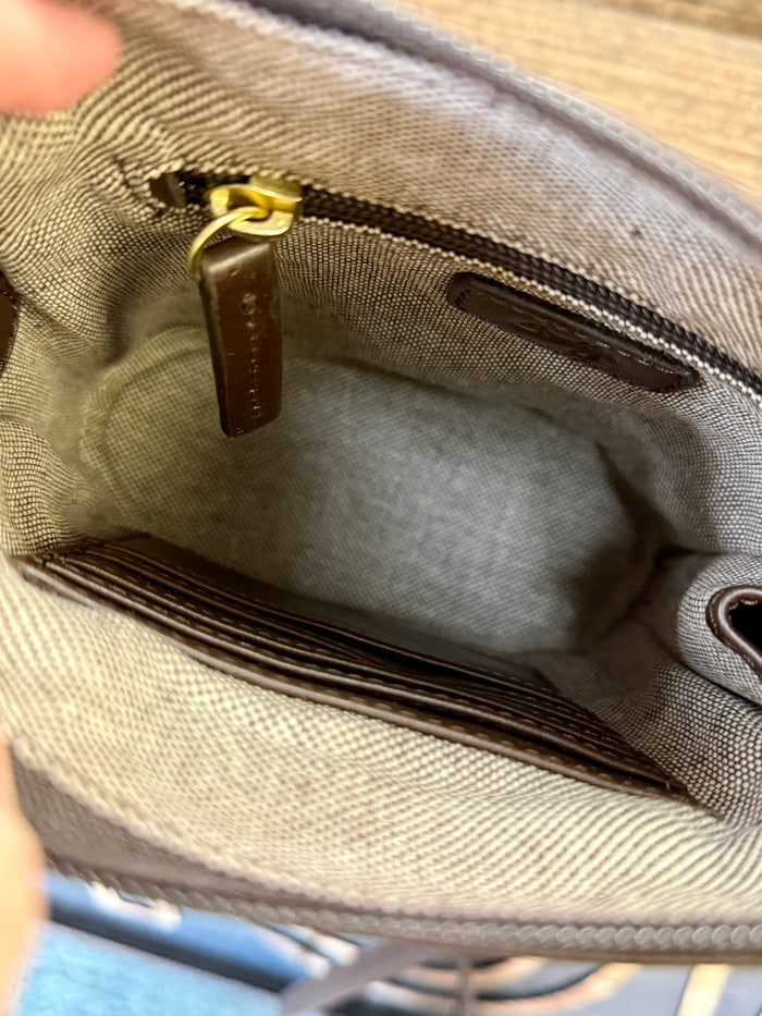 Open brown leather purse interior with beige lining, zip pocket and gold zipper pull