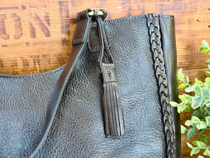 Dark brown leather tote top view with zipped closure, braided side panels, and hanging tassel