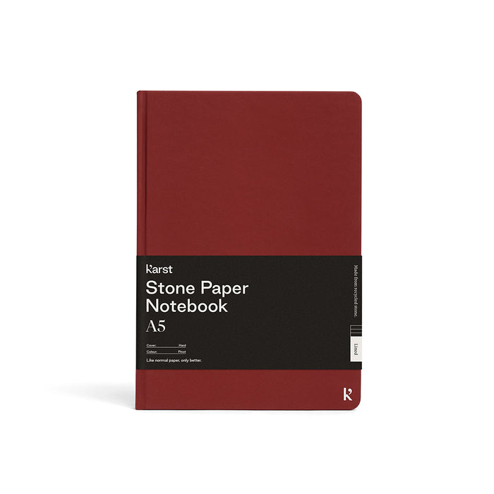 Karst A5 Stone Paper Notebook in deep red with hard cover and black branded belly band, displayed on a light gray background.