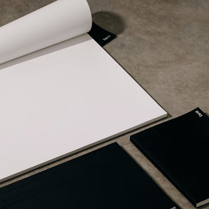 Open notebook with two black notebooks on a gray surface