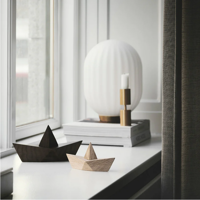 Two wooden boats on a surface with a modern lamp in the background.