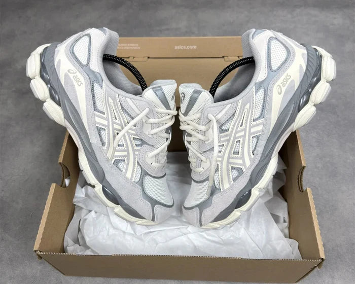 Pair of gray and white running shoes in a cardboard box on a gray background