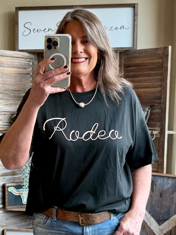 Black rodeo T-shirt worn by model, front shows white rope and Rodeo script