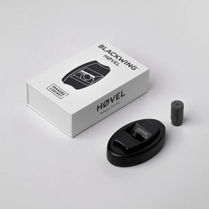 Angled view of the Blackwing × Makers Cabinet Høvel pencil plane displayed beside its white branded box and a small cylindrical blade container on a light gray background.