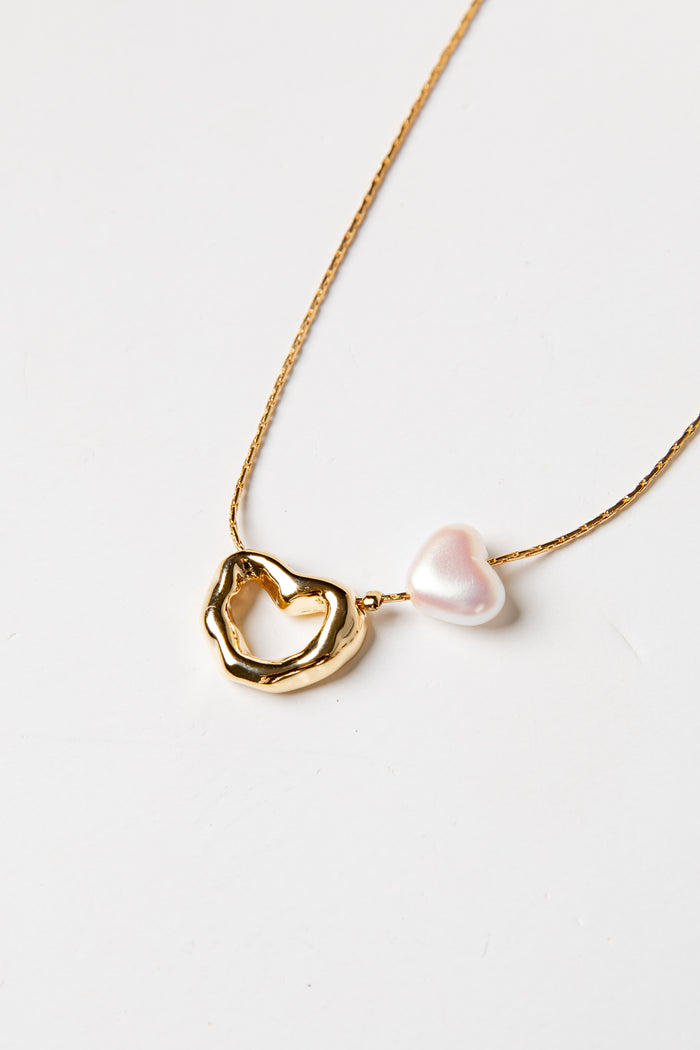 Gold necklace with a heart-shaped pendant and pearl on a white background