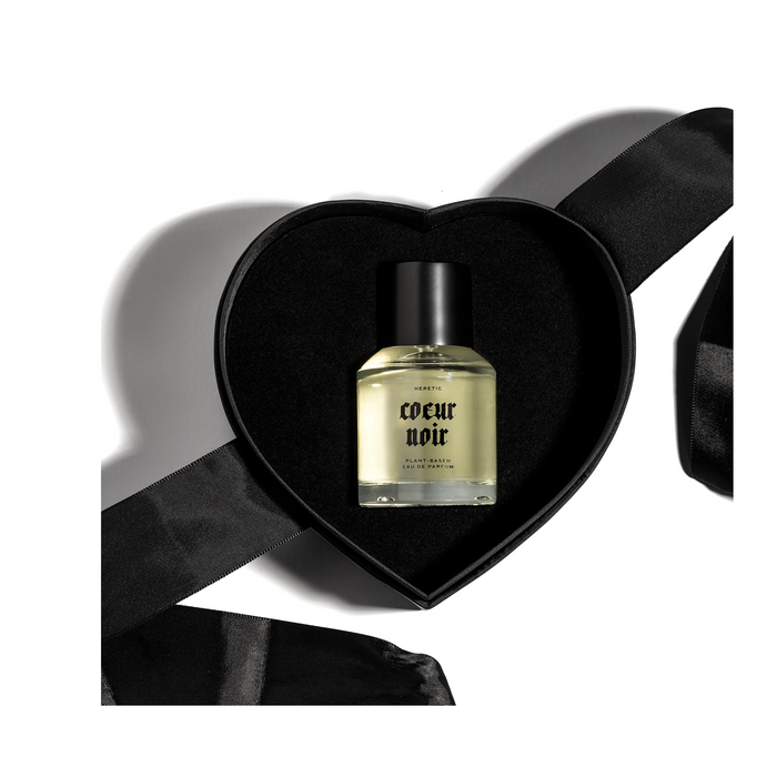 'Coeur Noir' perfume by Heretic laying in a black, heart shaped box with a black ribbon