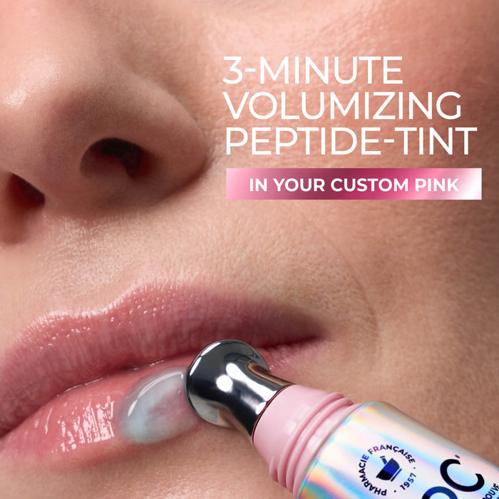 Close-up of a person's lips and nose area using a pink cosmetic device on the lower lip, with text reading '3-MINUTE VOLUMIZING PEPTIDE-TINT IN YOUR CUSTOM PINK.'.
