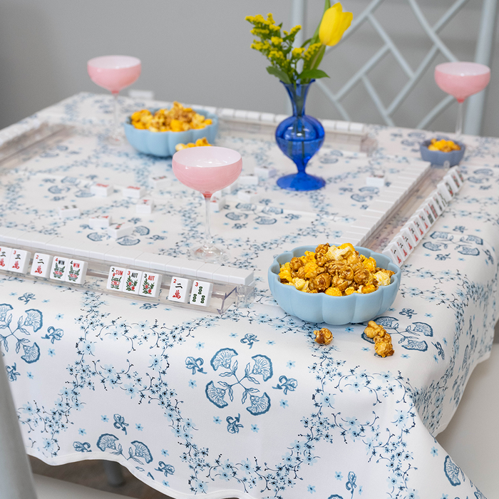Game table with blue and white patterned tablecloth, mahjong, and snacks.
