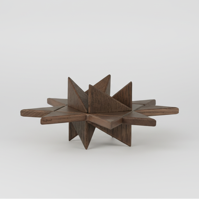 Geometric wooden star-shaped object crafted from smoked wood, composed of intersecting flat planes and pointed facets, showcasing rich dark wood grain and a sculptural matte finish on a plain white background.