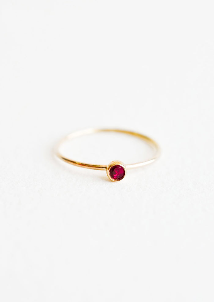 Yellow gold ring with slim band and small red garnet stone.