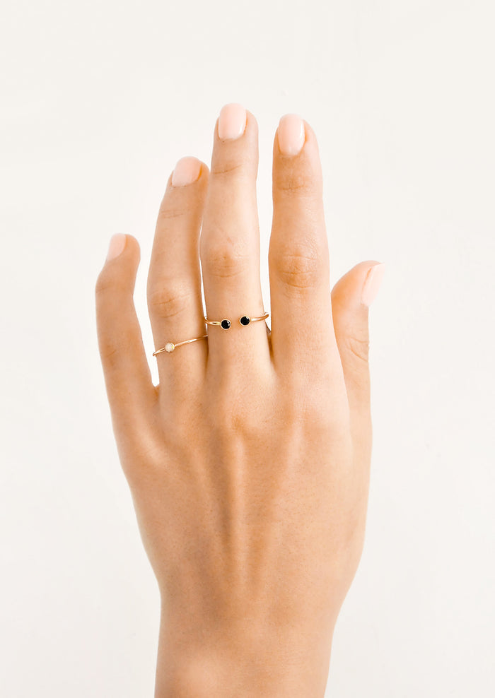 Model shot of hand wearing two gold rings with stones.