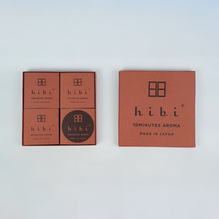 A hibi 10 Minutes Aroma gift set on a white background, with an open box on the left showing four brown inner boxes arranged in a grid and a closed matching hibi box on the right displaying the minimalist logo and branding.