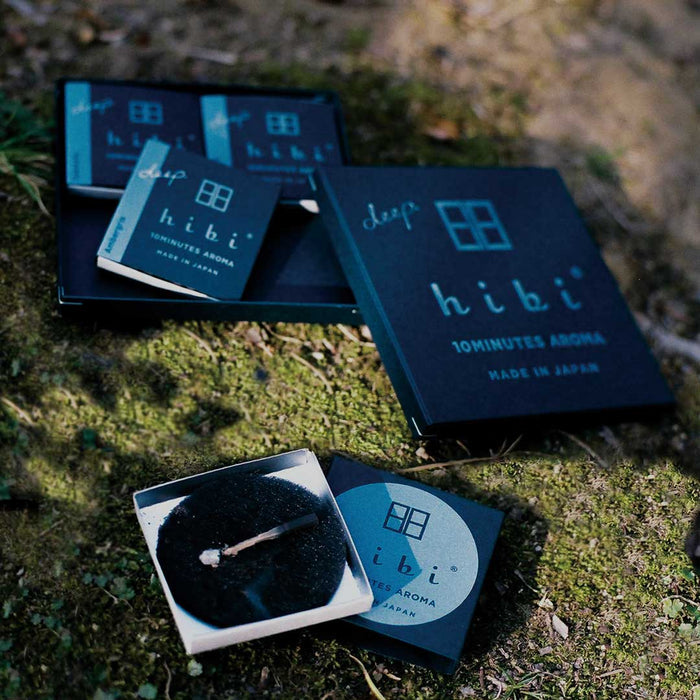 Hibi Deep incense matches gift set displayed outdoors on moss, featuring multiple match boxes, a burning incense match, and the black hibi aroma mat.