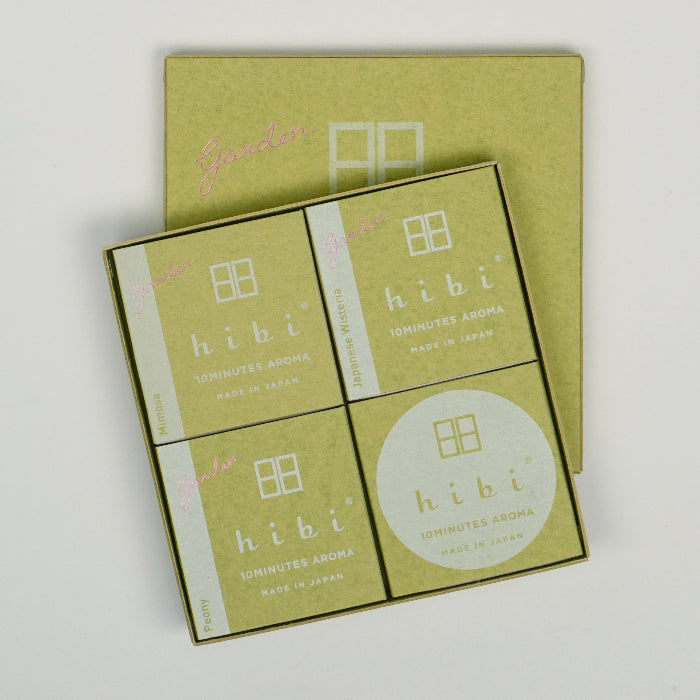 An open square hibi 10 Minutes Aroma gift box on a white background, showing four green-themed inner boxes arranged in a grid, with the matching green hibi box lid placed behind the open set.