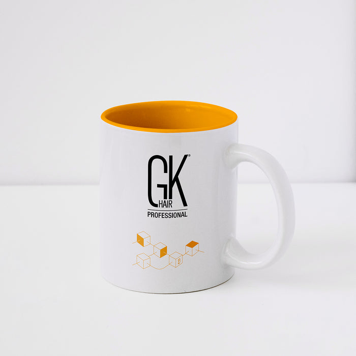 White ceramic mug with an orange interior, printed with the black GK Hair Professional logo and an orange cube graphic