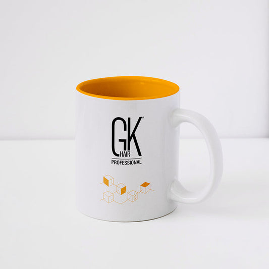 White ceramic mug with an orange interior, printed with the black GK Hair Professional logo and an orange cube graphic