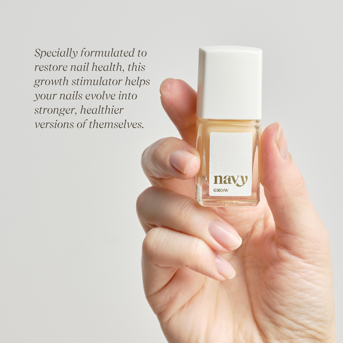 A nail growth treatment bottle held in a hand with bare nails with the brand name 'navy' displayed the bottle giving information on how it stimulates growth