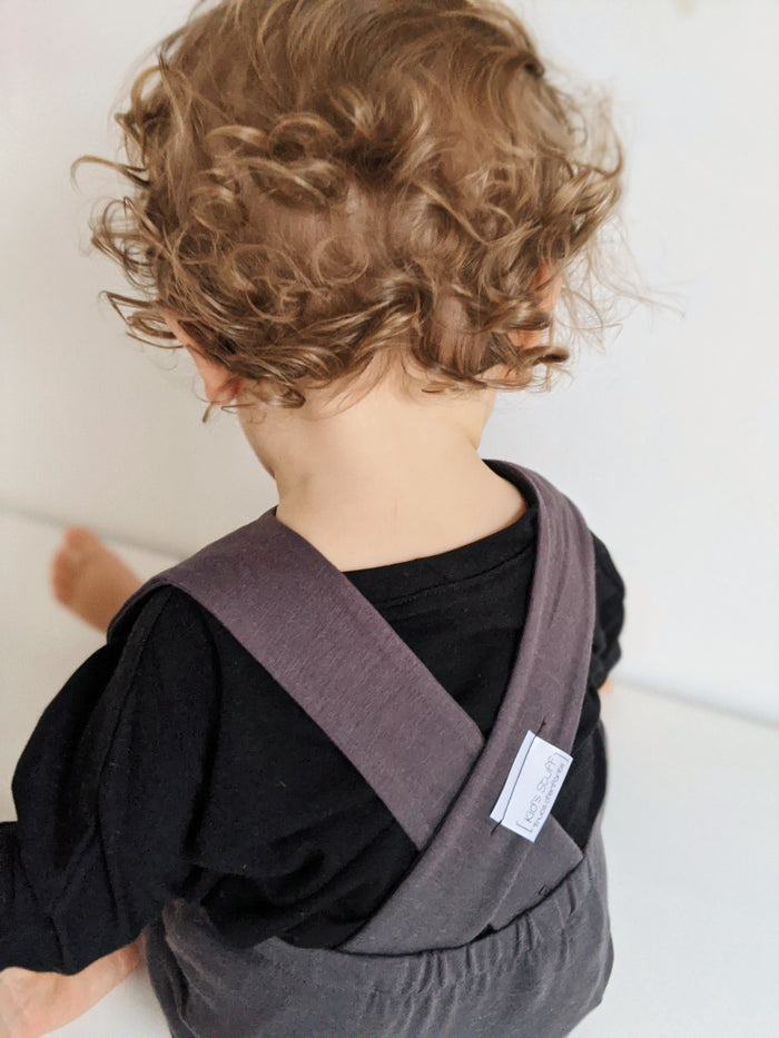 Dark grey grow-with-me overalls for toddlers and kids, made from soft, eco-friendly fabric. Adjustable straps and cuffs for a long-lasting fit. Ethically made in Canada.