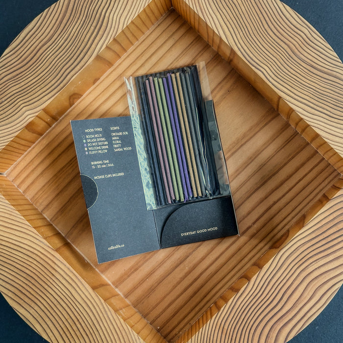 Open Collins Everyday Good Mood incense set displaying assorted colored incense sticks and scent guide, arranged on a carved wooden tray for stylish minimalist home fragrance presentation.