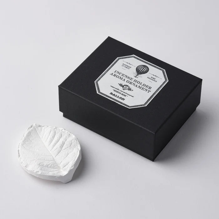 A white marble incense holder next to its black packaging box, which has a label that reads 'INCENSE HOLDER MARBLE'.