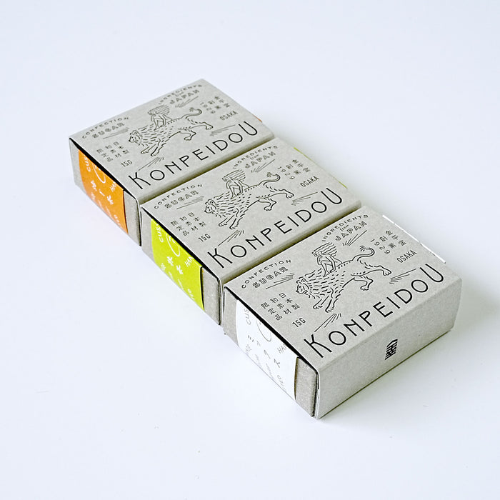 Four Konpeidou brand matchboxes arranged diagonally on a clean white background. The boxes are light gray with black printed graphics and text, with three showing colored ends in orange, yellow-green, and white.