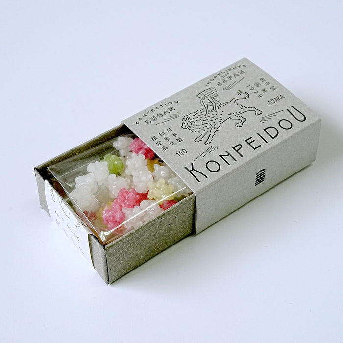 A matchbox-style package containing small translucent decorative beads or candy-like pieces in white, pink, and pale green, photographed on a clean white background. The box is printed with the brand name Kohpeidou and illustrated graphics.