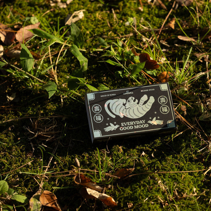 A box of Korea Edition incense is placed on a grassy surface with leaves, the box is black with white and green text and illustrations.