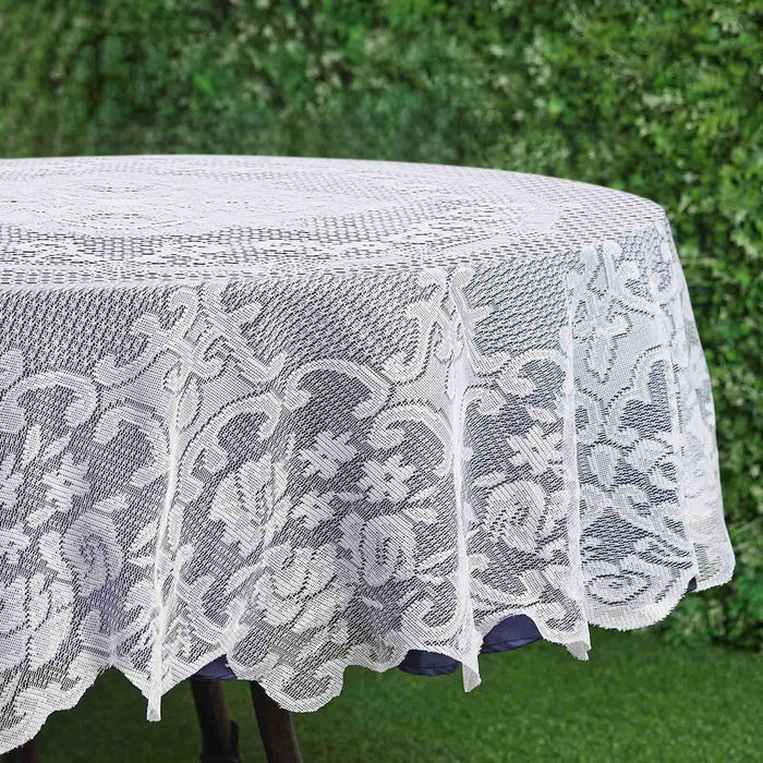 White lace tablecloth on a round table against a green background.